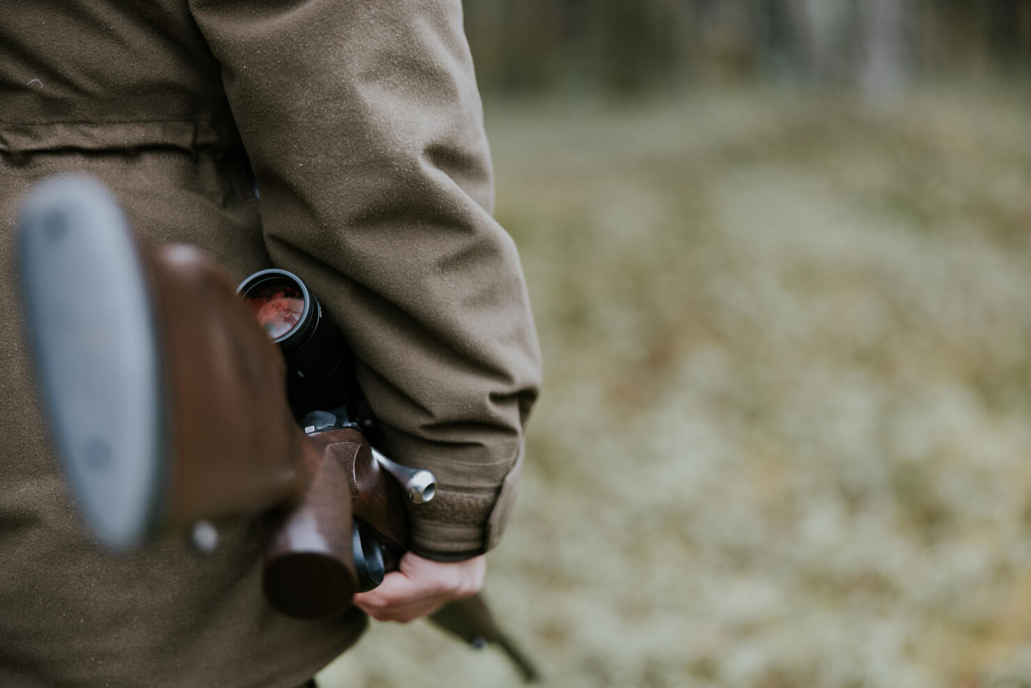 Close up shot of man with hunting rifle walking in the autumn forest