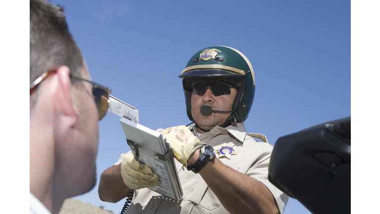 Police man writing man speeding ticket