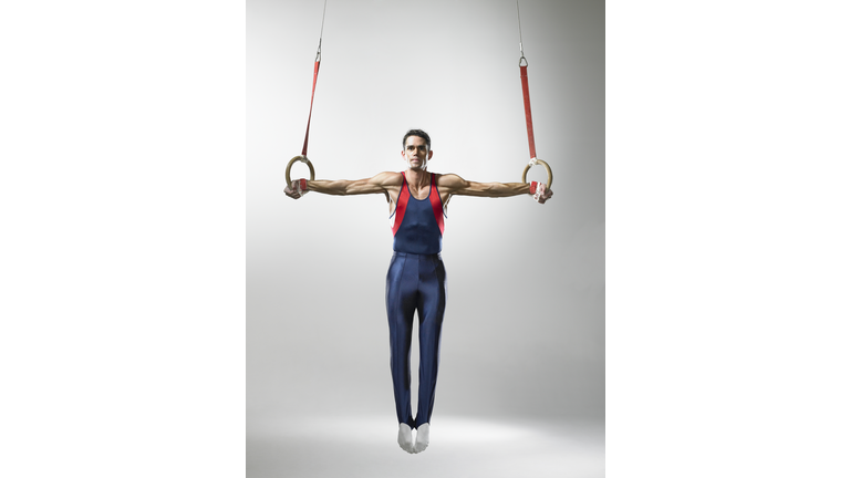 Male gymnast on rings, studio shot