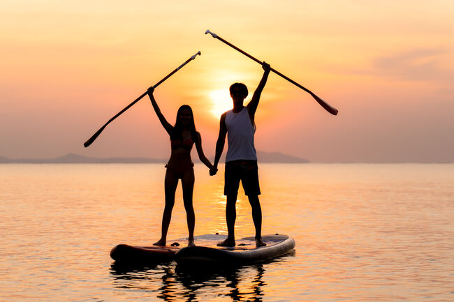 Stand up paddle board couple paddleboarding. Young Asian couple on summer vacation.