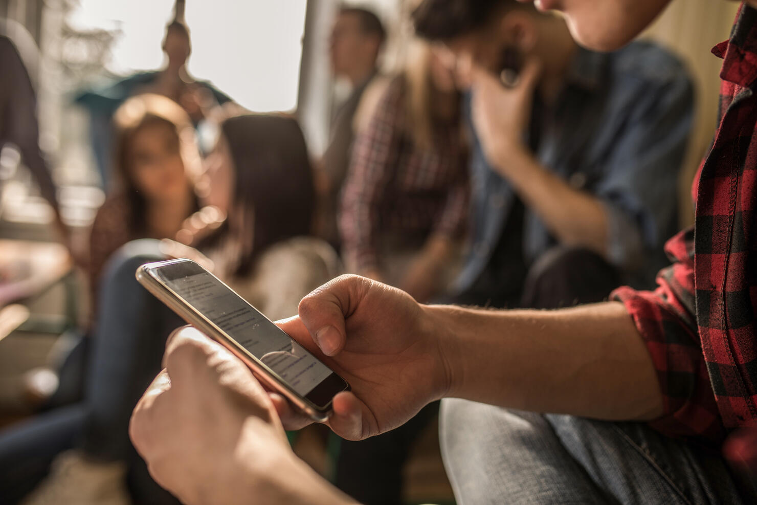 Close up of unrecognizable student using cell phone on a break in the classroom.