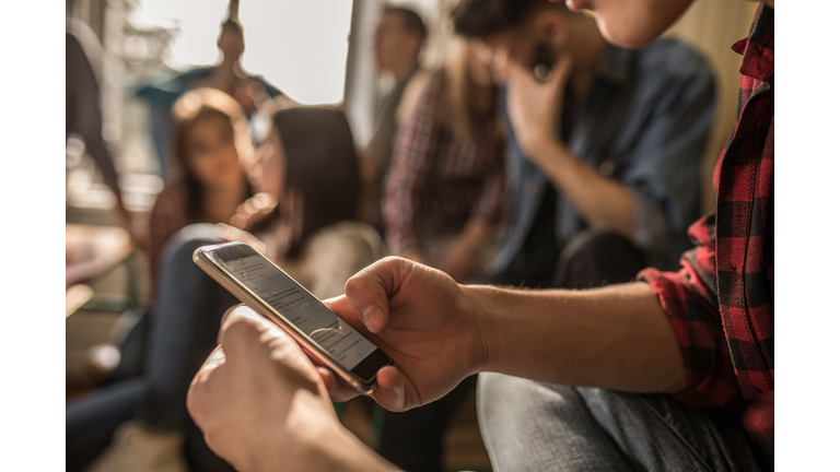 Close up of unrecognizable student using cell phone on a break in the classroom.