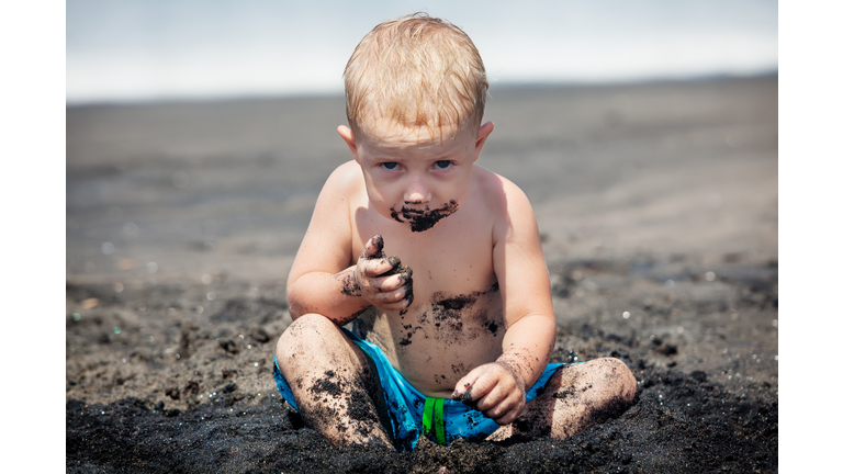 Happy dirty child play with sand on family beach vacation