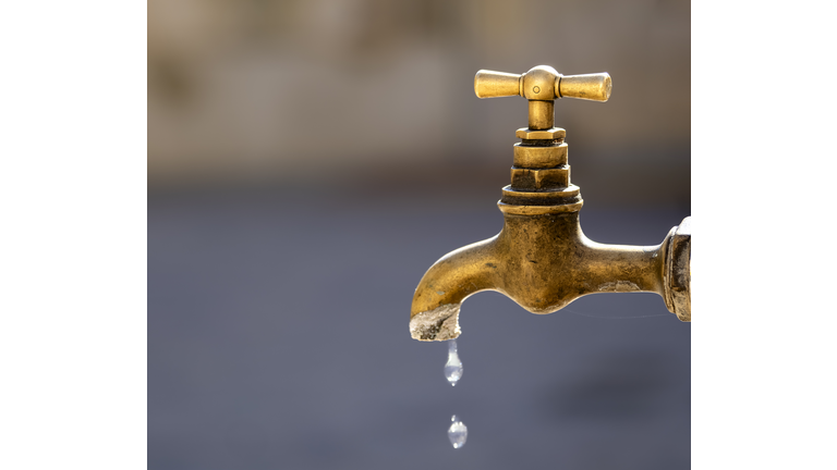 Outdoor drinking water faucet with dripping water drops.