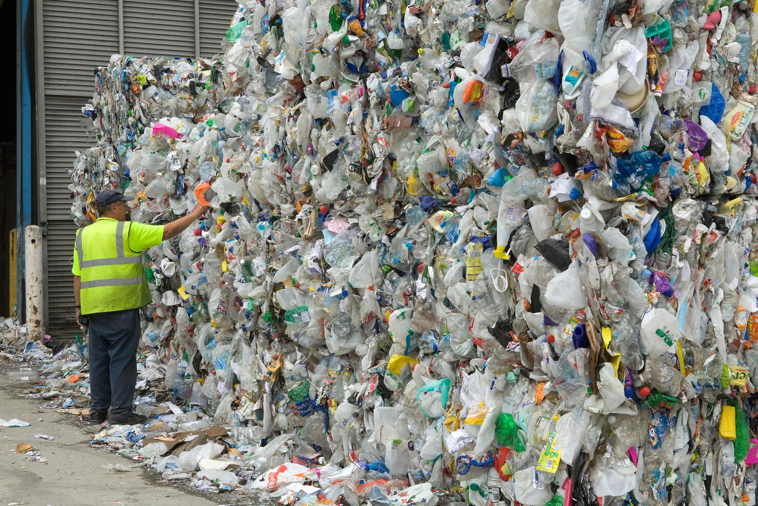 man examines bales of plastic waste bottles