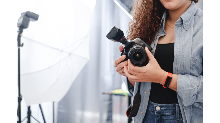 unknown photographer woman holding a professional camera on the studio.