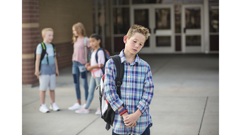 Sad boy feeling left out, teased and bullied by his classmates