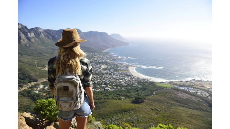 South Africa, Cape Town, woman standing looking at the coast during hiking trip to Lion's Head