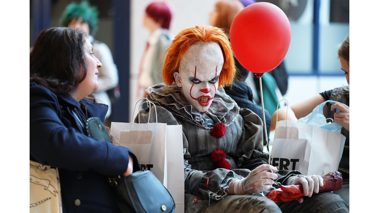 Scary clown Pennywise holding red balloon and looking at camera