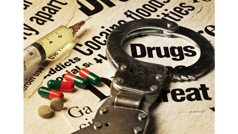 Syringe, pills and handcuffs on stained drug-related headlines