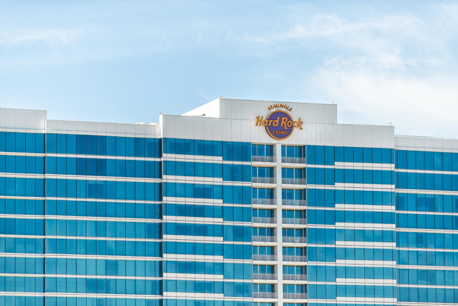 Seminole Hard Rock Cafe hotel and casino resort sign for famous restaurant in Florida exterior facade of modern glass building and blue sky