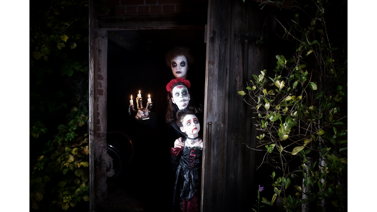 three kids in spooky halloween costumes in door of barn