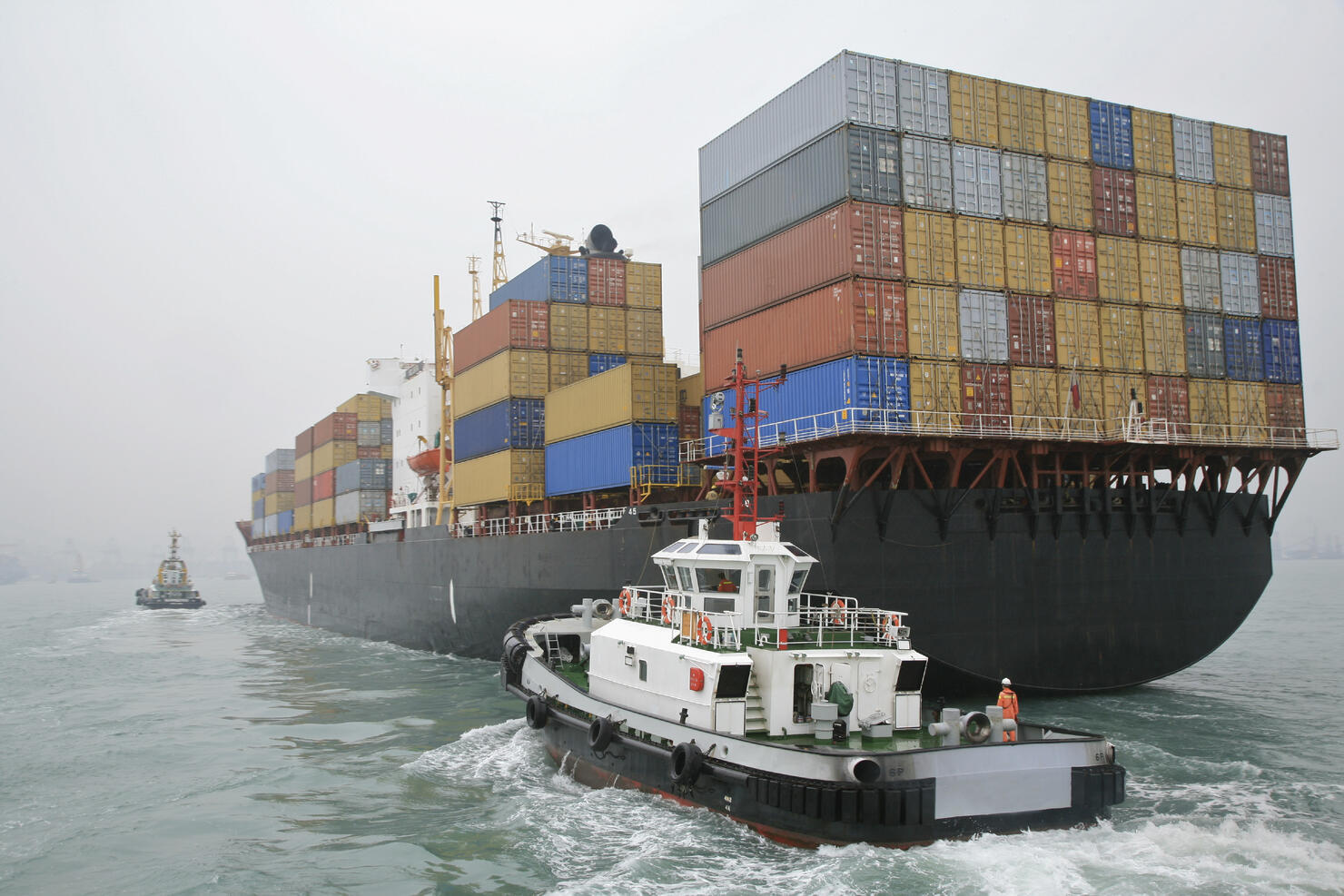 China, Hong Kong Harbor, tugboat sailing alongside container ship