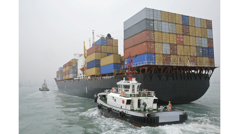 China, Hong Kong Harbor, tugboat sailing alongside container ship