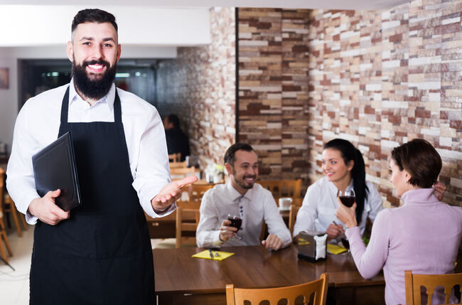 Waiter welcoming guests in restaurant