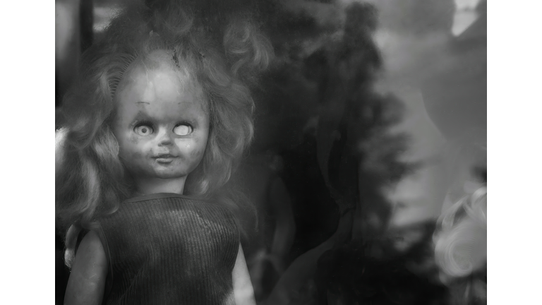 One-eyed old doll behind cloudy glass in black and white