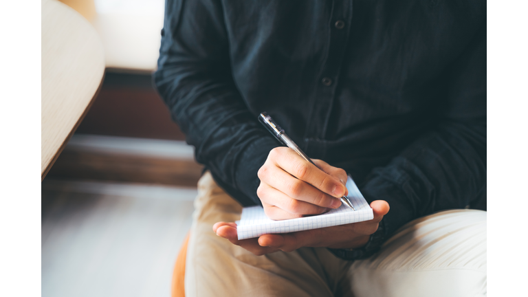 Young Asian man is making handwritten notes in a notepad