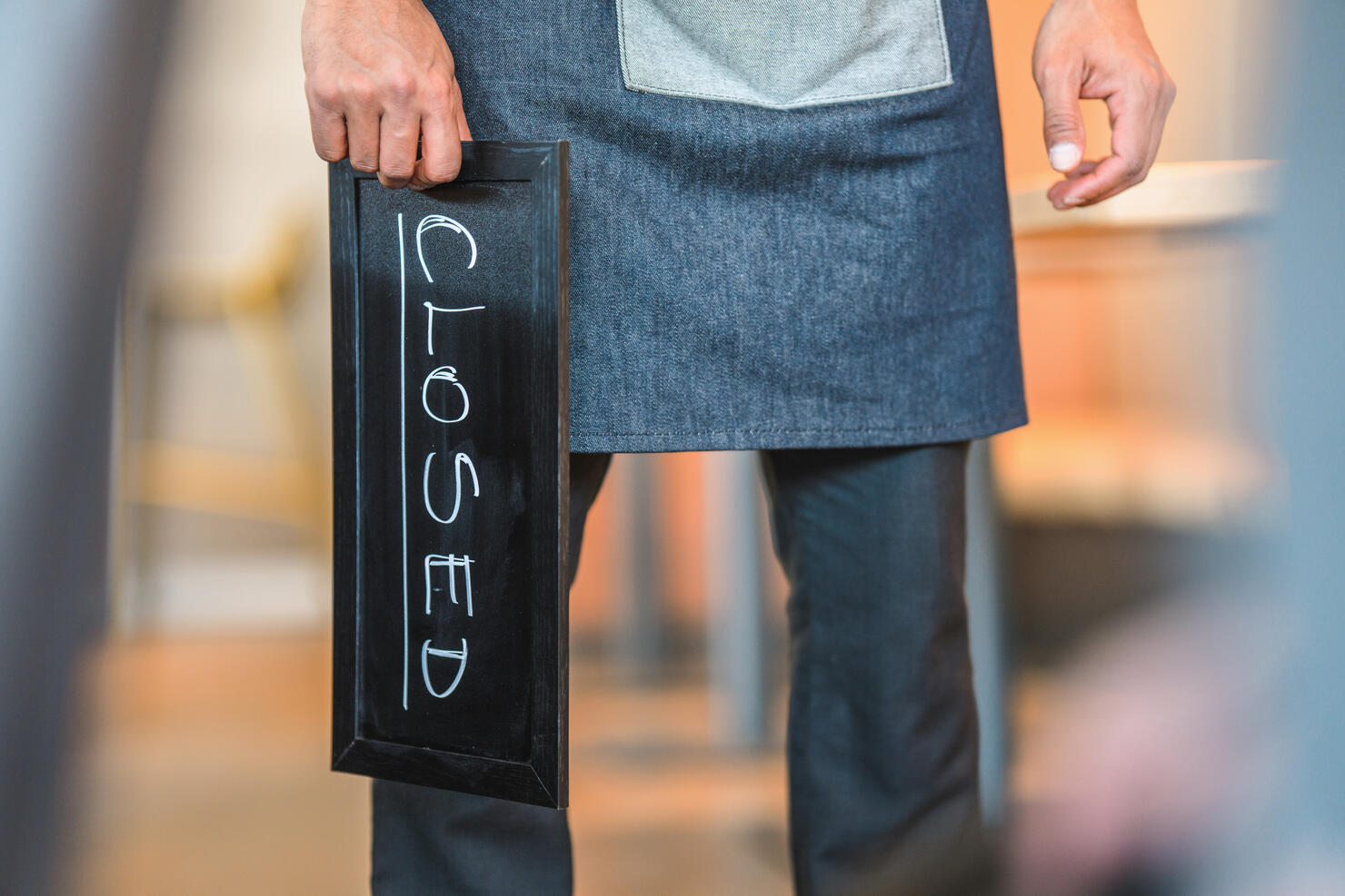 Mixed Race Waiter Holding a "Closed" Sign at the Entry of a Cafe