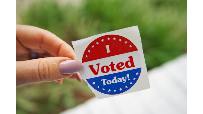 Woman holds I Voted sticker. Close-up view