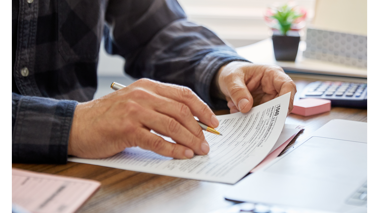 Close-up of a man holding a tax form, working from home