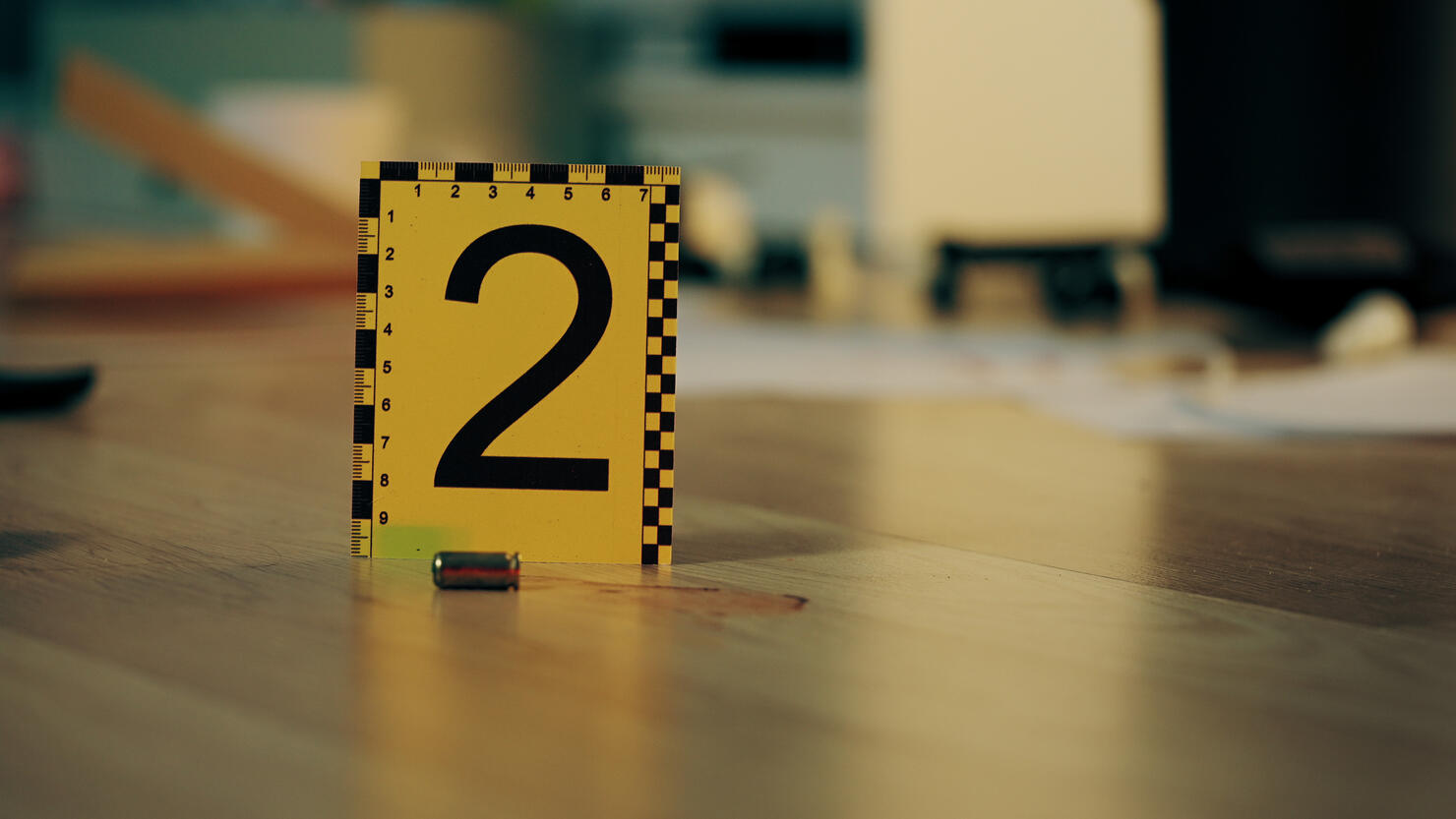 Close-up of a crime scene marker near a bullet casing at the crime scene, requiring forensic expertise