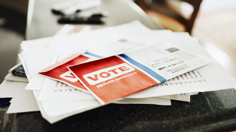 Mail in voting ballots sitting on the kitchen counter of a home