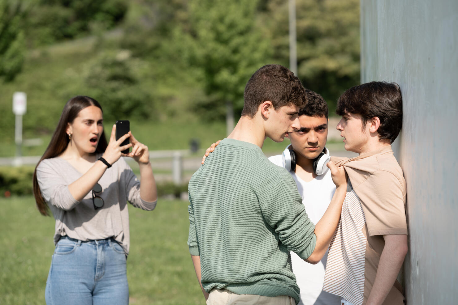 Two bullies menacing teenager boy and filming on phone