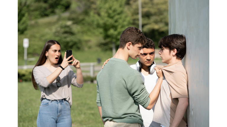 Two bullies menacing teenager boy and filming on phone