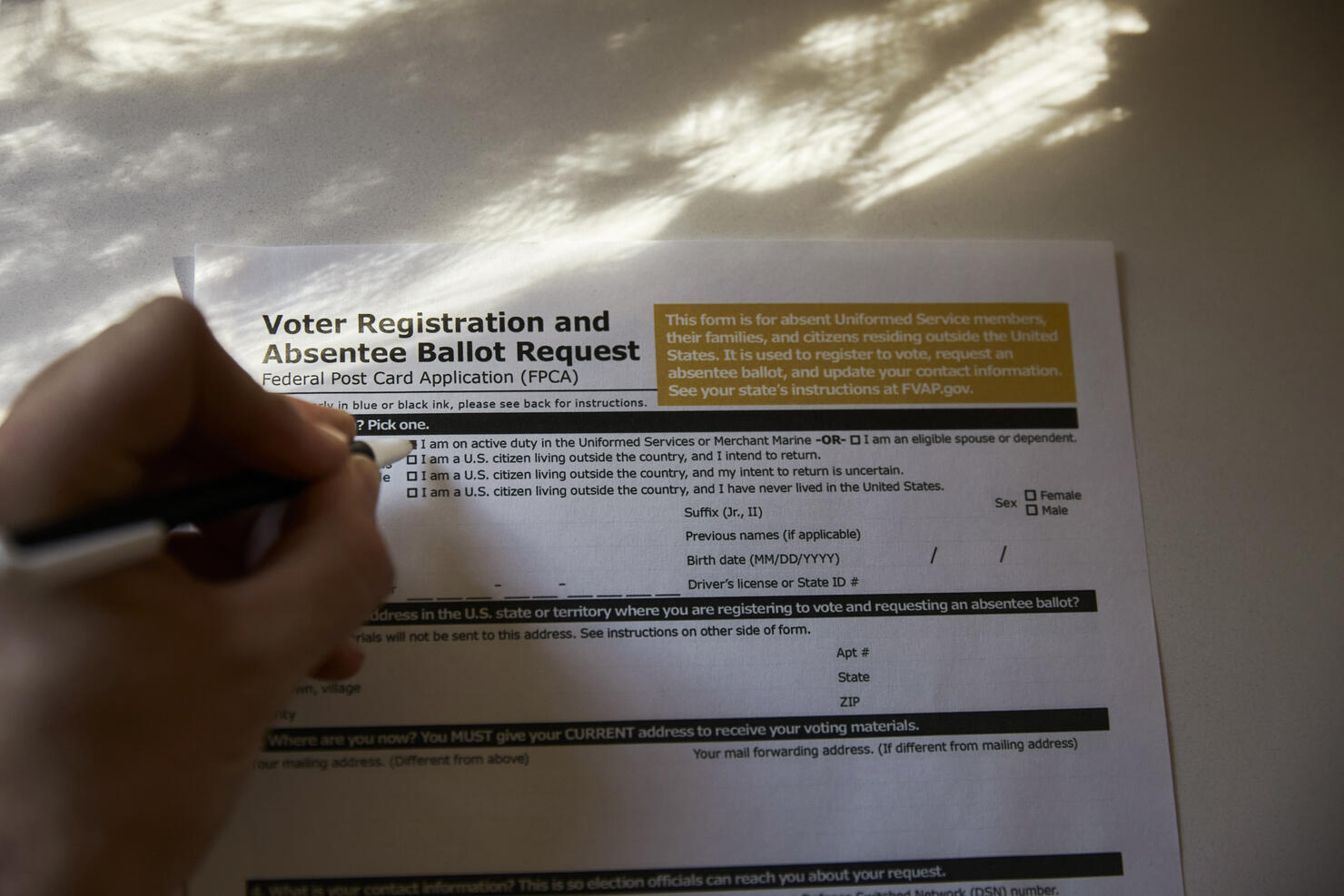 Overhead shot of a person filling out a voter registration and absentee ballot forum at home.