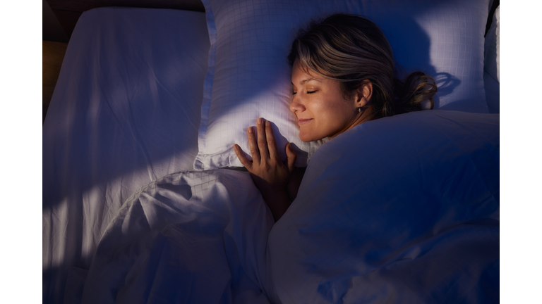 Above view of smiling woman sleeping in bed.