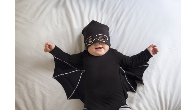 Baby boy dressed as a bat and wearing a mask