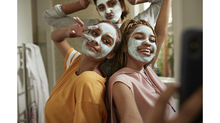 Happy woman taking selfie with friends wearing cream