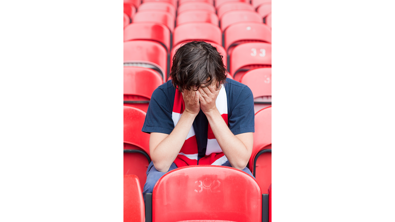 Disappointed football fan in empty stadium