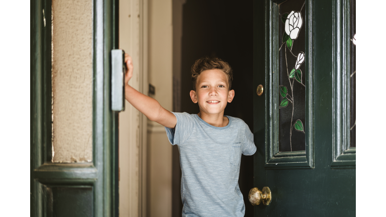 Portrait of smiling boy opening door