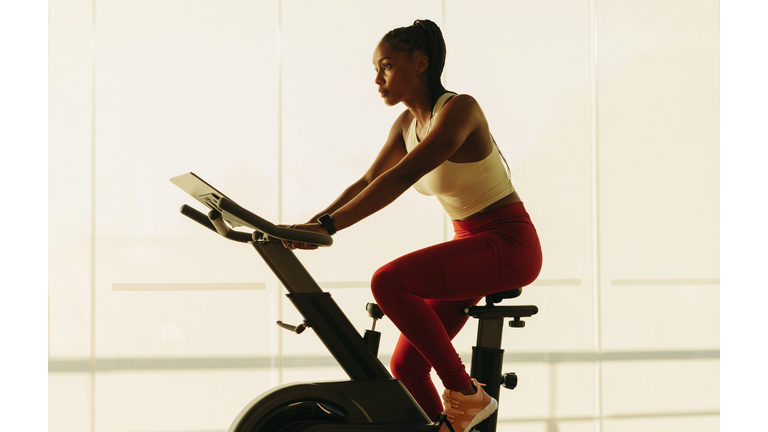 Healthy home workout: Sporty black female exercising on stationary bike