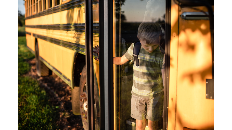 Child getting off the bus at bus stop after school