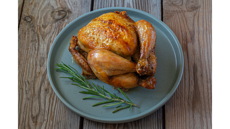 Thanksgiving fresh baked chicken (turkey) on a wooden background. Festive food.