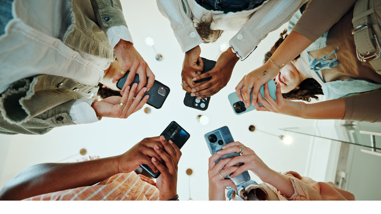 People, circle and phones for university registration, online and teamwork in education on campus. Students, low angle and huddle for project solidarity in college, collaboration and united learning