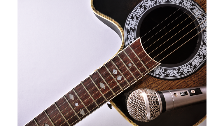 Acoustic guitar and microphone isolated on white table top