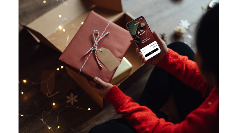 Young woman tracking delivery via smart phone for Christmas shopping online