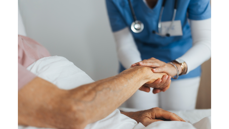 Close-up of caregiver holding senior client hand. Support from nurse to patient, taking care of elderly man in hospital. Emotional support and care in healthcare.