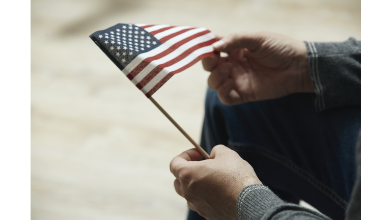 Midsection of man holding small American Flag