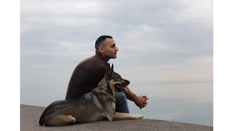 Man and dog looking over tranquil lake, profile