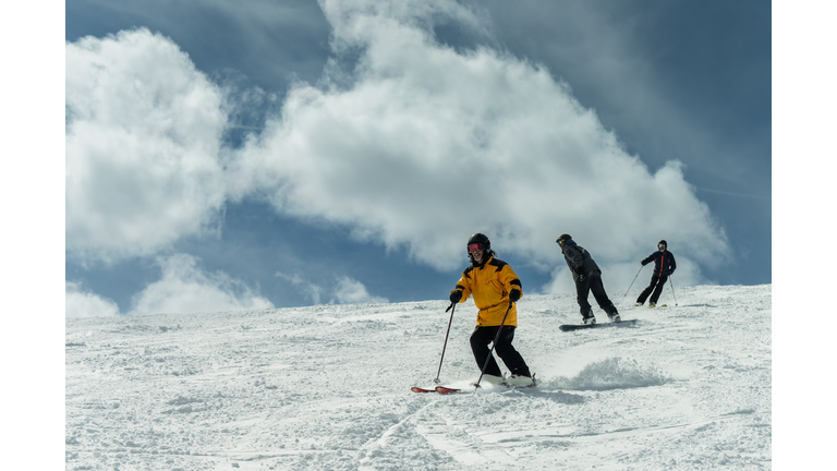 Low Angle View of Skiers and a Snowboarder Descending Towards the Camera