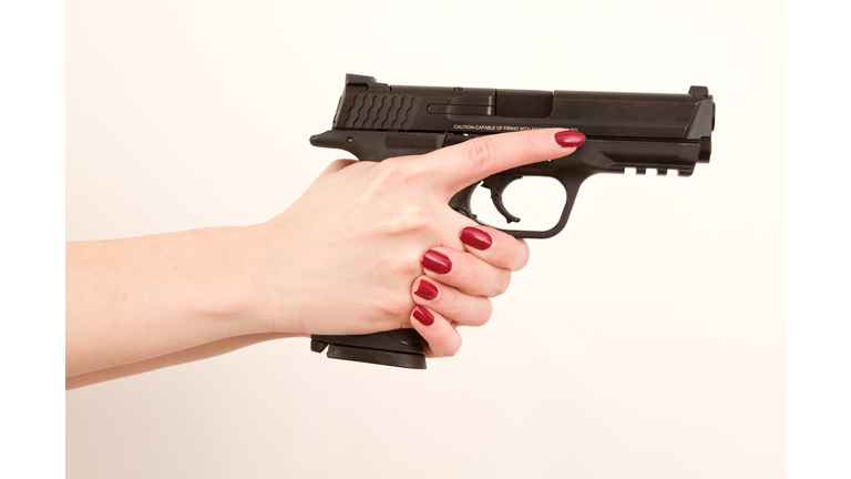 Woman holding pistol, finger off trigger