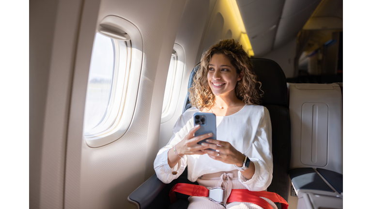 Female traveler using her cell phone in an airplane
