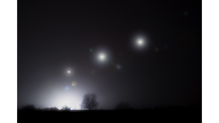 Glowing alien UFO lights floating in the sky. On a spooky foggy winters night