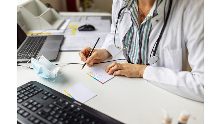 Doctor making notes while on video call with patient