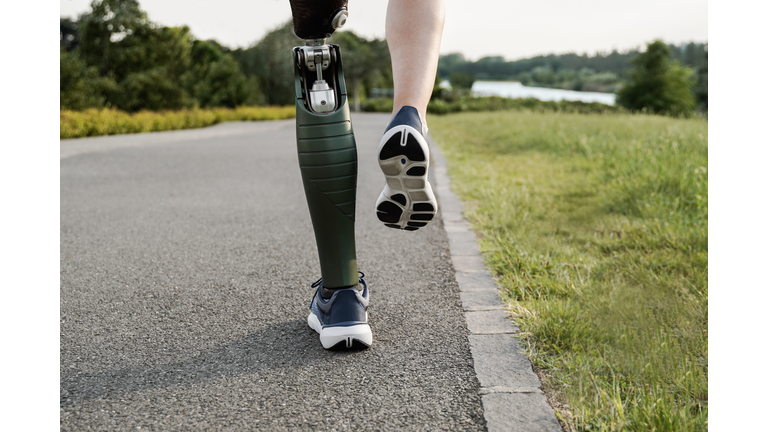 Sport man with prosthetic leg running training outdoor - Fitness and disability concept - Focus on prosthesis