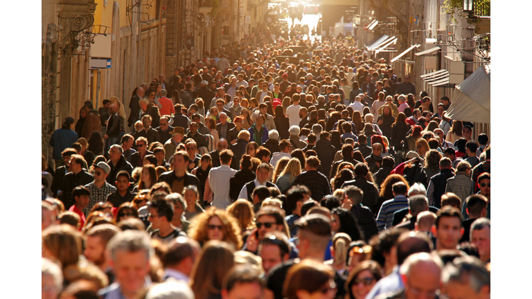 Crowd of people walking on street in downtown Rome, sunlight